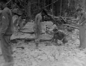 Capt. Trabeck and a black soldier setting dynamite under a boulder blocking the path of the Alaska Highway. 1942