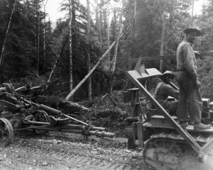 Black soldiers operating a dozer pulling an Adams grader over the Alaska Highway. 1942