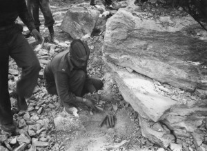Capt. Traback and a black engineer setting explosives under a boulder in the path of the Alaska Highway. 1942