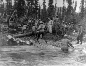 93rd Black soldiers handrolling logs for a bridge over Dead Man's Creek on the Alaska Highway. 1942