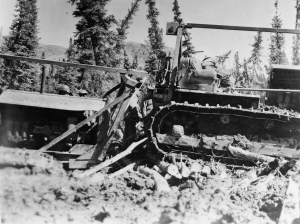 Along the Alaska Highway, one dozer is stuck in mud as a second dozer attempts to pull it free. 1942