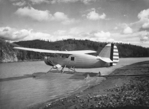 Les Cook, famous bush pilot and a one man support unit, anchored his plane on the shore of Teslin River. 1942