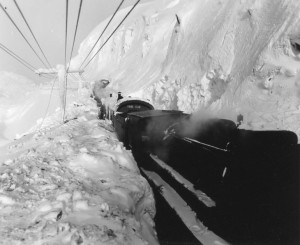 The White Pass and Yukon narrow gauge railroad sed a rotary plow during the winter to clear the tracks. Snow drifts were many feet high. One locomotive pulled and two locomotives pushed the railcars over the pass. 1942