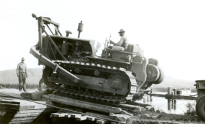 A Black Soldier operating a D8 bulldozer onto a barge crossing the Tagish River 1942.